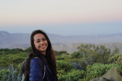 A smiling woman in front of a tropical green forest